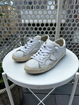 Phillippe Modell - Snygga vita sneakers från Philippe Model med klassisk låg siluett. Skorna har vita skosnören, diskret logga på sidan och bak, samt en beige sula. Tillverkade i läder med detaljer i mocka för en stilren look. 100% äkta, köpta från Miinto för ca 4000kr förra året och maina de ett tag! Säljer de nu för att de har blivit för små. Har tyvärr inte kvar lådan men dustbagen medkommef!