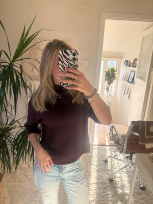 Vinröd stickad tröja med halvpolo - Mysig vinröd stickad tröja med halvpolo och halvlånga ärmar. Tröjan har en avslappnad passform och är perfekt att styla med jeans. Materialet ser mjukt och bekvämt ut, perfekt för kyligare dagar. Storlek 158/164, ginayoung