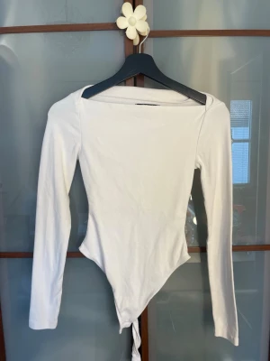 Vit långärmad body Gina Tricot - Säljer en enkel och stilren vit body från Gina Tricot i storlek XS. Bodyn har långa ärmar, rundad halsringning och är gjord i mjukt stretchigt material som sitter snyggt på kroppen. Perfekt att matcha med jeans eller kjol.