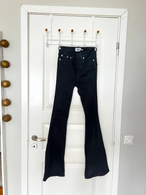 Svarta utsvängda jeans XXS 157 - Säljer ett par svarta jeans från lager 157 i storlek XXS med full längd. Modellen har hög midja och utsvängda ben, vilket ger en riktigt snygg siluett. Klassisk femficksdesign.dragkedja fram och vanliga fickor där bak. Perfekta för dig som gillar trendiga och bekväma jeans. 