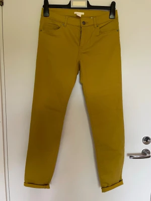Gula raka byxor i storlek 38, H&M - Snygga gula jeans med rak passform och klassisk femficksdesign. Tillverkade i bomull med lite polyester och elastan för extra komfort och stretch. Perfekta för dig som vill sticka ut med färg i vardagen. Stl 38, oanvända 