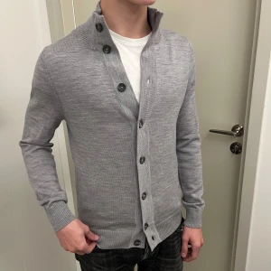 Cardigan - En stilren ljusgrå cardigan från märket Suitsupply i 100% merinoull. Suitsupply är känt för bekväma  premiumtyger och modern passform - ett märke som ofta jämförs med Oscar Jacobson och Stenströms.  Nypris omkring 1 800-2 000 kr. Hör gärna av dig om du har några frågor🤩💬