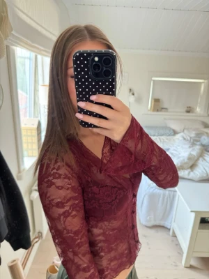 Vinröd lace topp från Gina  - Säljer min vinröda spetstopp från Gina. V-ringning och långa ärmar. Blusen har ett figurnära snitt och fina spetsdetaljer över hela tyget. Perfekt för jul eller annat firande! Endast använd 1 gång så mycket bra skick!💗