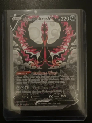 Pokémonkort galarian Moltres V - Säljer ett Pokémonkort med Moltres V-motiv. Kortet har en mörk och färgstark design med svart, röd och rosa illustration av Moltres. Det är inplastat i ett skyddsfodral och har 220 HP. Perfekt för samlare eller Pokémonfans!