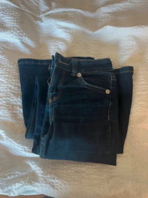 Mörkblå bootcut jeans - Snygga mörkblå bootcut jeans. Jeansen har normal midja, bälteshällor och silverfärgade knappar. Perfekta och passar till det mesta.