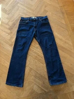 Levis 517 bootcut jeans - Säljer ett par mörkblå Levis 517 med bootcut passform och klassisk femficksdesign. Jeansen har normal midja och är tillverkade i denim. Midjan är storlek 33 men sitter som 32-33 och längden är storlek 30 men sitter som 30-32. Bra skick och väldigt enkla att styla!