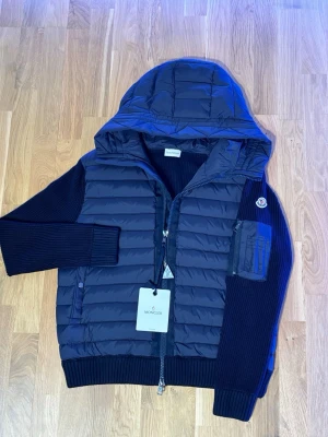 Mörkblå cardigan från Moncler - Snygg mörkblå pufferjacka från Moncler. Den är i storlek xxl men sitter som en M. Tror det blivit fel i och med att min andra jacka också var så. Ny jacka utan skador alls och med lappen kvar