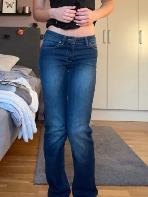 Mörkblå bootcut jeans - Säljer ett par mörkblå jeans med klassisk femficksdesign och normal midja. Jeansen har en lätt tvättad look och raka ben som går ut lite nedtill. Materialet är denim med lite stretch för skön passform. Perfekta till vardagslooken!