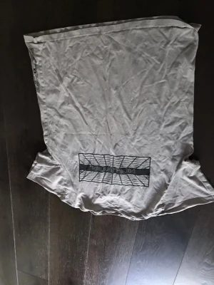 Vit/ljus grå Hollister t-shirt  - Säljer en vit t-shirt från Hollister med ett svart grafiskt tryck på bröstet. T-shirten har klassisk passform med tryck både på ryggen och bröstet. Perfekt för dig som gillar enkel och stilren streetwear.