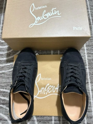 Loub skor - Stilrena svarta sneakers från Christian Louboutin i mocka med klassisk låg profil och svarta skosnören. Insidan är ljusbeige och skon har en minimalistisk design som passar till många olika outfits. Pris kan diskuteras vid snabbaffär