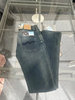 Nudie Jeans Slim Jim, Scraped Blue Grey (W29 L34) - Säljer ett par riktigt snygga Nudie Jeans i modellen Slim Jim. Tvätten "Scraped Blue Grey" ger en perfekt, naturligt använd look som bara blir snyggare med tiden. Jeansen är i mycket fint skick och kommer med originaltags kvar. Den klassiska Slim Jim-passformen är tidlös och enkel att styla till både t-shirt och skjorta. Specifikationer: • Modell: Slim Jim • Tvätt: Scraped Blue Grey • Storlek: W29 L34 • Material: 62% bomull, 38% PBT • Skick: Mycket bra, tags kvar Skicka ett DM vid frågor 