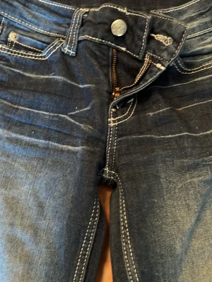 Mörkblå bootcut jeans med kontrastsömmar - Säljer ett par mörkblå bootcut jeans med snygga slitningar och kontrastsömmar. Jeansen har klassisk femficksmodell, dragkedja och knapp i midjan. ❣️🥰 Jeansen är knappt andvända och passar nog folk som är 145 -150 ish ❣️ 