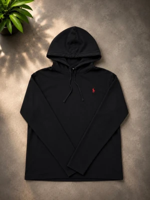 Svart hoodie från Polo Ralph Lauren - Snygg svart hoodie från Polo Ralph Lauren med klassisk huva och dragsko. Liten röd logga broderad på bröstet ger en clean look. Tillverkad i mjukt material som känns skönt mot huden. Perfekt för dig som gillar stilrena och tidlösa plagg.