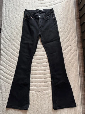 Svarta bootcut jeans i storlek 34 - Säljer ett par svarta bootcut jeans i storlek 34 från Perfect Jeans. Jeansen har klassisk femficksmodell, hög midja och utsvängda ben. Snygga detaljer med nitar och knapp i silver. Perfekta för dig som gillar en retroinspirerad look.