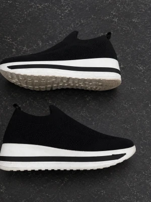 Svarta slip-on sneakers med platåsula - Säljer ett par svarta slip-on sneakers med stickad ovandel och tjock vit platåsula med svart rand. Skorna har en modern, minimalistisk look och är lätta att ta på tack vare den strumpliknande designen. Perfekta för dig som gillar streetstyle och komfort.