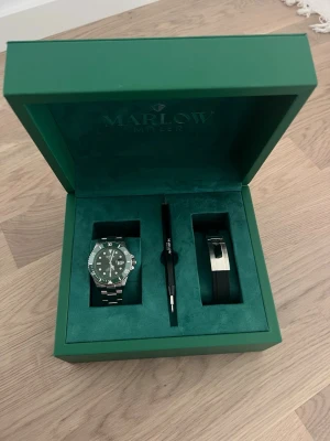 Marlow Miller klockset - Rostfritt stål och vattentät upp till 10ATM/100M. Armbandsur med ett extra matchande armband i silikon samt ett verktyg för att enkelt byta band eller justera storleken. Har detaljer som lyser i mörkret och plastskydd kvar på baksidan.