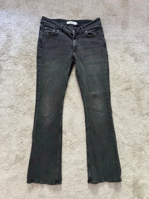 Svarta bootcut jeans med stretch - Snygga svarta bootcut jeans från junkyard med klassisk femficksmodell och stretchigt material för skön passform. Jeansen har normal midja och subtila slitningar för en avslappnad look. Perfekta till sneakers eller boots.
