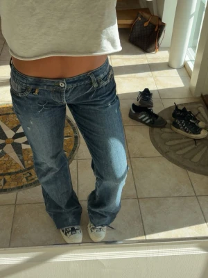 lågmidjade jeans med slitningar  - fina jeans i en mer baggy modell + blåa detaljer på bakfickorna. saknas en knapp (bild 4) men inget som syns på. skriv för fler bilder💓