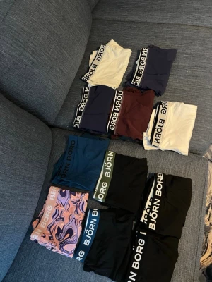 13-pack Björn Borg kalsonger i mixade färger - Säljer ett 13-pack Björn Borg kalsonger i olika färger och mönster. Färgerna inkluderar svart, marinblå, vinröd, beige, grön, blå och ett par med abstrakt mönster. Alla har bred resår med Björn Borg-logga. Klassisk boxermodell i mjukt och stretchigt material.
