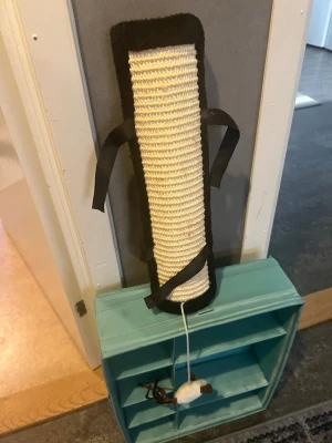 Klösbräda och leksaksmus till katt - Klösbräda/klösmatta för katt med kardborreband 🐱  Praktisk klösbräda för katt som kan fästas runt exempelvis stolsben, bordsben eller andra smalare möbelben med hjälp av kardborrebanden på baksidan. Kan även placeras på annat lämpligt ställe.  Klösytan ger katten möjlighet att klösa och vässa klorna samtidigt som möblerna kan skonas. Har även en liten hängande leksak längst ner för extra stimulans. 🐾  Skick: Begagnad och har några fläckar/bruksspår, se bilder. Fungerar fortfarande som den ska oc