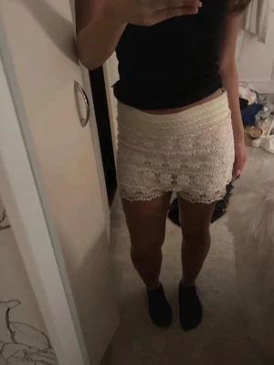 Beige spetskjol med volangdetaljer - Säljer en söt och feminin beige kortkjol med flera lager spets och volangdetaljer. Kjolen har en tight passform och är perfekt för dig som gillar romantisk stil. Resår i midjan för extra komfort.
