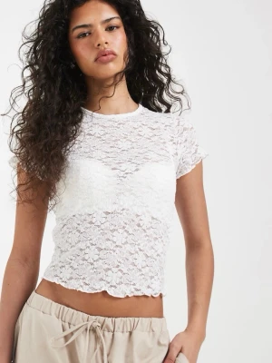 Vit spets topp med kort ärm - Säljer en vit, croppad topp i spets med korta ärmar och rund hals. Toppen är genombruten och har ett feminint, romantiskt uttryck med vågig kant nertill. Perfekt att styla över ett linne eller bh för en trendig look.