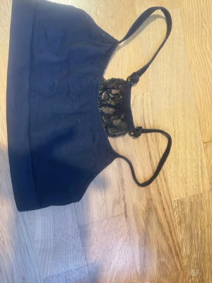 Svart bralette med spetsdetalj - Snygg svart bralette med tunna axelband och dekorativ spets framtill. Mjuk och stretchig.