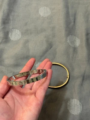 Silverfärgat armband med skruvdetaljer - Snyggt armband i silverfärg med ikoniska skruvdetaljer runt om. Armbandet har en stilren och modern design som passar perfekt till alla outfits. Tillverkat i metall och har en rund form. Vattenfast Snyggt armband i silverfärg med ikoniska skruvdetaljer runt om. Armbandet har en stilren och modern design som passar perfekt till alla outfits. Tillverkat i metall och har en rund form.