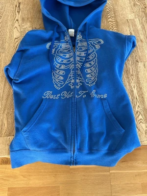 Rhinestone hoodie  - Blå ziphoodie med huva och fickor framtill. Saknar endas fåtal stenar