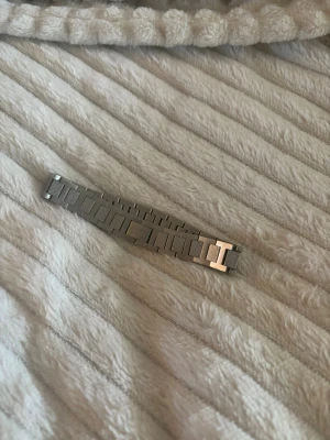 Lacoste armband i rostfritt stål - Säljer ett snyggt armband i silverfärgat rostfritt stål med rektangulära länkar och graverade detaljer. Armbandet har en modern och stilren design som passar perfekt till din vardagsstil. Lätt att matcha med andra accessoarer. Den är även perfekt att ge bort som gåva. Storlek 20cm.