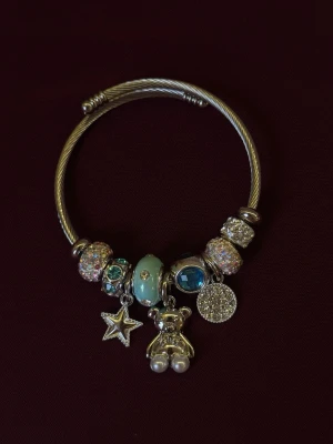 Silverfärgat armband med berlocker - Armband i silverfärgad rostfritt stål med flera gulliga berlocker. 