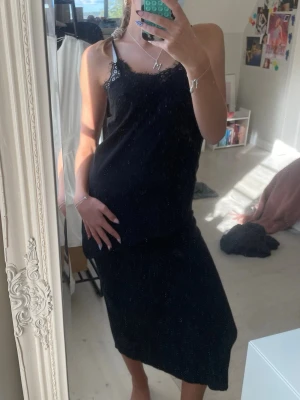 Svart långkjol i satin - Säljer en svart långkjol i mjukt satinliknande material. Kjolen har en enkel och stilren design med rak passform och slät midja. Perfekt att matcha med olika toppar för en trendig look.