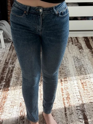 Mörkblå skinny jeans med hög midja - 40 - Säljer ett par mörkblå skinny jeans med hög midja och klassisk femficksdesign. Jeansen har smal passform hela vägen ner och är tillverkade i stretchigt denimtyg för extra komfort. Perfekta till en avslappnad look.