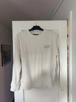 Beige sweatshirt från Lee - Säljer en stilren beige sweatshirt från Lee i regular fit. Tröjan har rund halsringning, långa ärmar och diskret Lee-logga broderad på bröstet. Perfekt för dig som gillar enkel och klassisk streetwear.