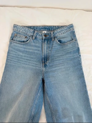 Blå wide fit jeans med hög midja - Säljer ett par ljusblå wide fit jeans med ultrahög midja och klassisk femficksdesign. Jeansen har raka ben och är tillverkade i bomull för en skön och avslappnad look. Perfekta för dig som gillar en loose och trendig stil.