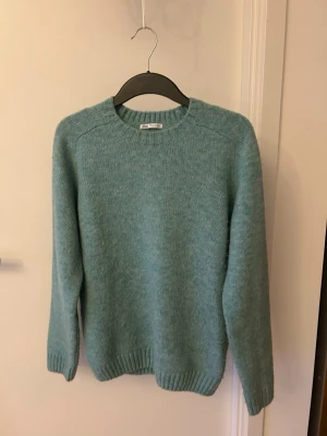 Turkos  stickad tröja - Mysig turkos stickad tröja med rund halsringning och långa ärmar. Tröjan har en enkel, klassisk design med ribbstickade muddar vid ärmslut och nederkant. Perfekt för kyliga dagar och lätt att matcha med olika outfits.