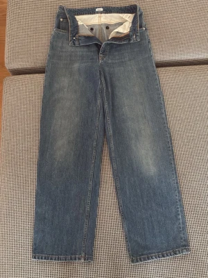 Filippa K key jean storlek 29 - Klassiska blå jeans med rak passform och hög midja. Jeansen har fem fickor och stängs med knapp och dragkedja. Tillverkade i denim med lätt tvättad look och subtila slitningar framtill.