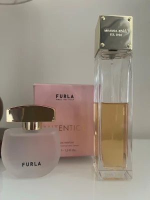 Parfymset 2 st Furla Autentica Eau de Parfum samt Michael Kors Sexy Amber Eau de Parfume - Parfymset 2 st  1) Furla Autentica Eau de Parfum är en doft med mousserande och saftiga noter från italienskt modehus Furla. Den har ett hjärta av pion och körsbärsblommor, insvept i kashmirträ, patchouli och mysk. En chypre-doft. 30 ml Endast testat.  2) Michael Kors Sexy Amber Eau de Parfum är en doft med huvudackord av amber, vita blommor och träiga noter. Doften beskrivs som pudrig och varmt kryddig. 100 ml, mer än hälften är kvar.  Jag säljer fler fina plagg, skor, accessoarer, parfymer och