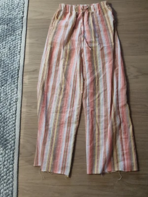 Randiga linnebyxor i pastellfärger - Säljer ett par luftiga linnebyxor. Har sprättqt upp de längst ner,passar 170-175.  #baggyjeans #lowwaist jeans #cargobyxor #vida jeans #flarejeans #lågmidja #rakajeans #kostymbyxor #mjukisbyxor #oversizedhoodie #ziphoodie #stickadtröja #corsettopp #offshoulder #babytee #linne med spets #oversized tshirt #stickadväst #maxikjol #y2k #vintage #streetwear #oldmoney #cleangirl #basic #festkläder #vardagskläder #unisex #oversized #fitted #cozy #retro #zara #hm #bikbok #ginatricot #nelly #nakd