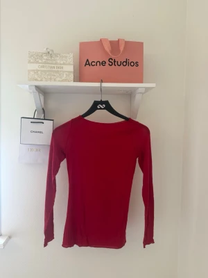 Intimissmi tröja - Säljer en enkel och stilren röd långärmad topp med rund hals. Toppen har en tight passform och är tillverkad i ett mjukt material som sitter skönt mot kroppen. Perfekt att matcha med jeans eller kjol för en clean look. Finns två små hål (se bild 3) men inget som märks 