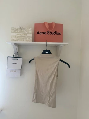 Beige topp - Säljer en beige ärmlös polotopp i mjukt material. Toppen har en hög hals och figurnära passform som ger en clean och stilren look. Perfekt att styla med jeans eller kjol för en trendig vibe.