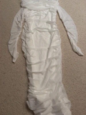 Vit långärmad meshklänning - Trendig vit långärmad klänning i mesh med åtsittande passform och rynkade detaljer längs hela klänningen. Perfekt för dig som vill ha en stilren och modern look med transparenta inslag och figurnära siluett.