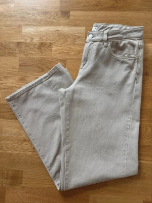 Beiga vida jeans  - Säljet ett par beiga jeans från gina tricot. Jeansen är lågmidjade och har vida ben. Benen har en snedskuren söm vilket gör att dom faller superfint. Använda enstaka gånger. Normala i storlek 