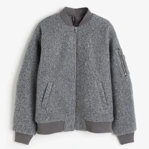 Grå bomberjacka fodrad  - Säljer oanvänd jacka från H&M i grå ”ull” vadderad bomberjacka. Divided. Silver detaljer med dragkedja. 