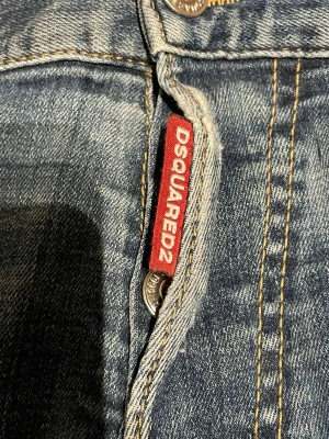 Blå slitna jeans från Dsquared2 - Säljer ett par blå jeans från Dsquared2 med slitningar, små hål och färgstänk men storlek M men passar S oxå 