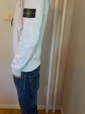 Vit hoodie med dragkedja från Stone Island - Säljer en vit hoodie från Stone Island med dragkedja framtill och klassisk logopatch på vänster ärm. Hoodien är i storlek S. Om du har några frågor är det bara att skriva, pris kan diskuteras.