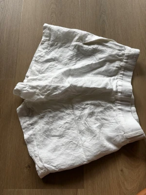 Vita linneblandade shorts - Snygga vita shorts i linneblandning med hög midja och bred resår i midjan. Perfekta för varma dagar och ger en avslappnad men fräsch look. Passar till allt från t-shirt till skjorta och är ett måste i sommargarderoben.