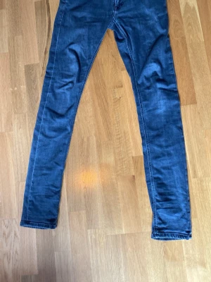 Mörkblå slim fit jeans - Säljer ett par mörkblå slim fit jeans med klassisk femficksdesign och raka ben. Jeansen har kontrastsömmar och är tillverkade i ett mjukt denimtyg som ger en skön passform. Perfekta för dig som gillar en enkel och stilren look.