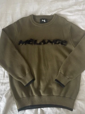 Olivgrön stickad tröja Mélange - MÉLANGE ”whatever i wear they copy” tröja. Använd ett fåtal gånger, inga defekter. Säljer pga att jag beställde fel storlek