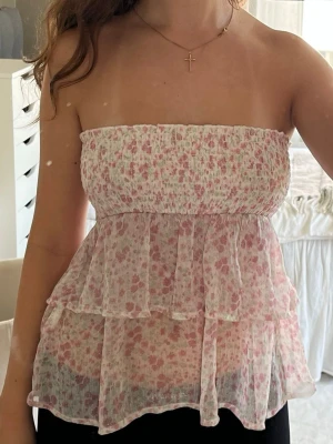 Blommig topp med volanger - Supersöt blommig topp som är smockad upptill över bysten med volanger nertill. Axelbanden är avtagbara så man kan välja om man vill ha den som en tubtopp eller ett linne💓 Toppen är i storlek 158/164 från Gina Tricots barnavdelning men sitter som en vanlig xs/s